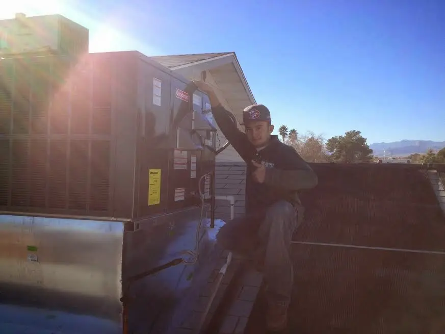 HVAC technician performing AC Tune-Up on a rooftop unit in Iowa Colony